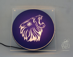 Quadratisches Acryl-Leuchtschild mit wei� leuchtendem L�wenkopf auf dunklem, blauem Hintergrund. Schwarzes Kabel.