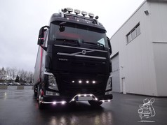Schwarzer Volvo FH LKW von vorne mit gl�nzender Numberplate-Leiste und hellen wei�en LEDs.