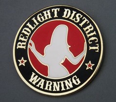 Runder gold-schwarzer Pin mit rotem Kreis, wei�er Frauensilhouette und "REDLIGHT DISTRICT WARNING" Text.