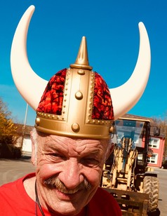 Wikingerhelm mit goldener Basis, rotem Scandi Pl�sch und gro�en wei�en H�rnern, getragen von einem l�chelnden Mann.