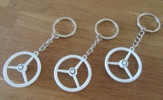 Wei�e Scandi Schl�sselanh�nger Old School Lenkrad mit silbernen Ringen auf Holzuntergrund.