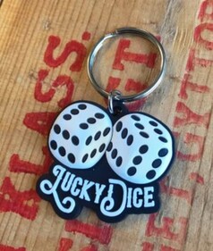 Schl�sselanh�nger mit wei�en W�rfel-Motiven und schwarzem Lucky Dice Schriftzug auf Holzuntergrund.