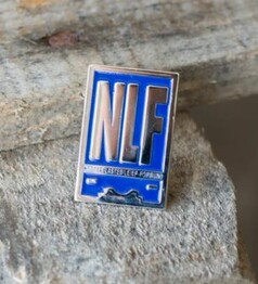 Rechteckiger Scandi Pin NLF in Blau und Silber mit NLF-Schriftzug.