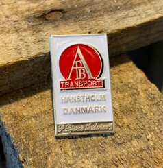 Scandi Pin: Wei�er Emaille-Pin mit rotem AB TRANSPORT Logo, HANSTHOLM DANMARK und P. Bjarne Andersen Schriftzug.