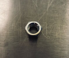 Silberne Mutter f�r US Antennen mit Innengewinde auf metallischem Untergrund.