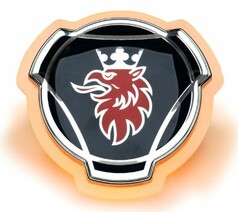 Original Scania Emblem auf einer orange beleuchteten Acrylplatte, die eine leuchtende Kontur erzeugt.