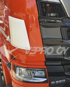 Wei�er Windabweiser aus Kunststoff am orangefarbenen Scania LKW, neben dem schwarzen K�hlergrill und Scheinwerfer.