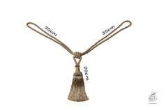 Goldfarbene Kordel mit Quaste aus geflochtenem Material auf wei�em Hintergrund.