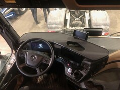Schwarzer Fahrertisch mit Lochmuster und Ausschnitt im Cockpit eines Mercedes Actros LKW.