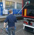 Mann reinigt schwarzen LKW mit einer Vikan LKW Waschb�rste (gr�n/rot) und Teleskop-Stiel, erzeugt Schaum.