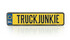 Gelber Pin in Form einer Kennzeichenplatte mit schwarzem "TRUCK JUNKIE" Schriftzug und blauem NL-Feld.