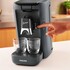 Dunkelgraue Senseo Kaffeepadmaschine von Philips. Eine Hand bedient die Maschine, davor stehen Gl�ser.
